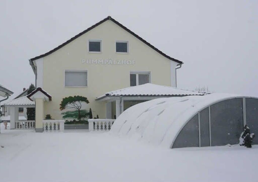 A two-story building with a snow-covered roof and a sign that reads "PUMPPALZHOF".
