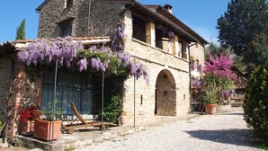 A stone building with a rustic exterior, featuring an arched doorway and a gravel driveway.