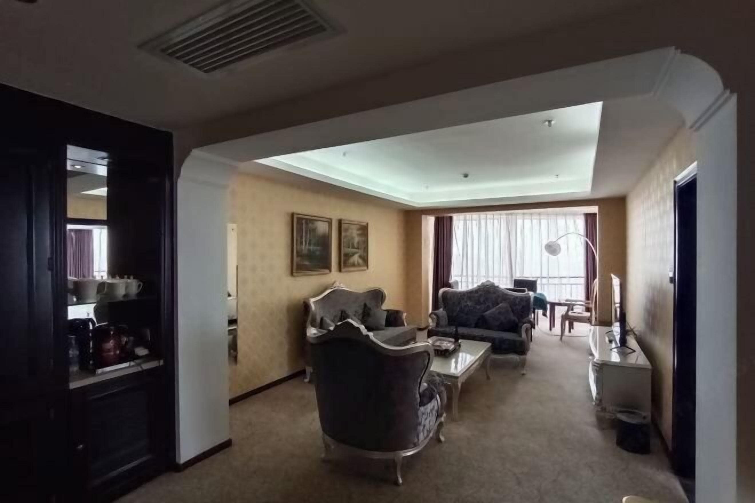 A living room with a sofa, armchair, coffee table, and a television.