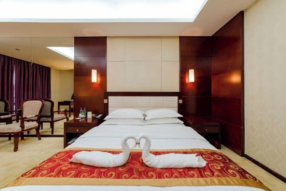 A hotel room with a large bed, two bedside tables, a desk, and a chair.