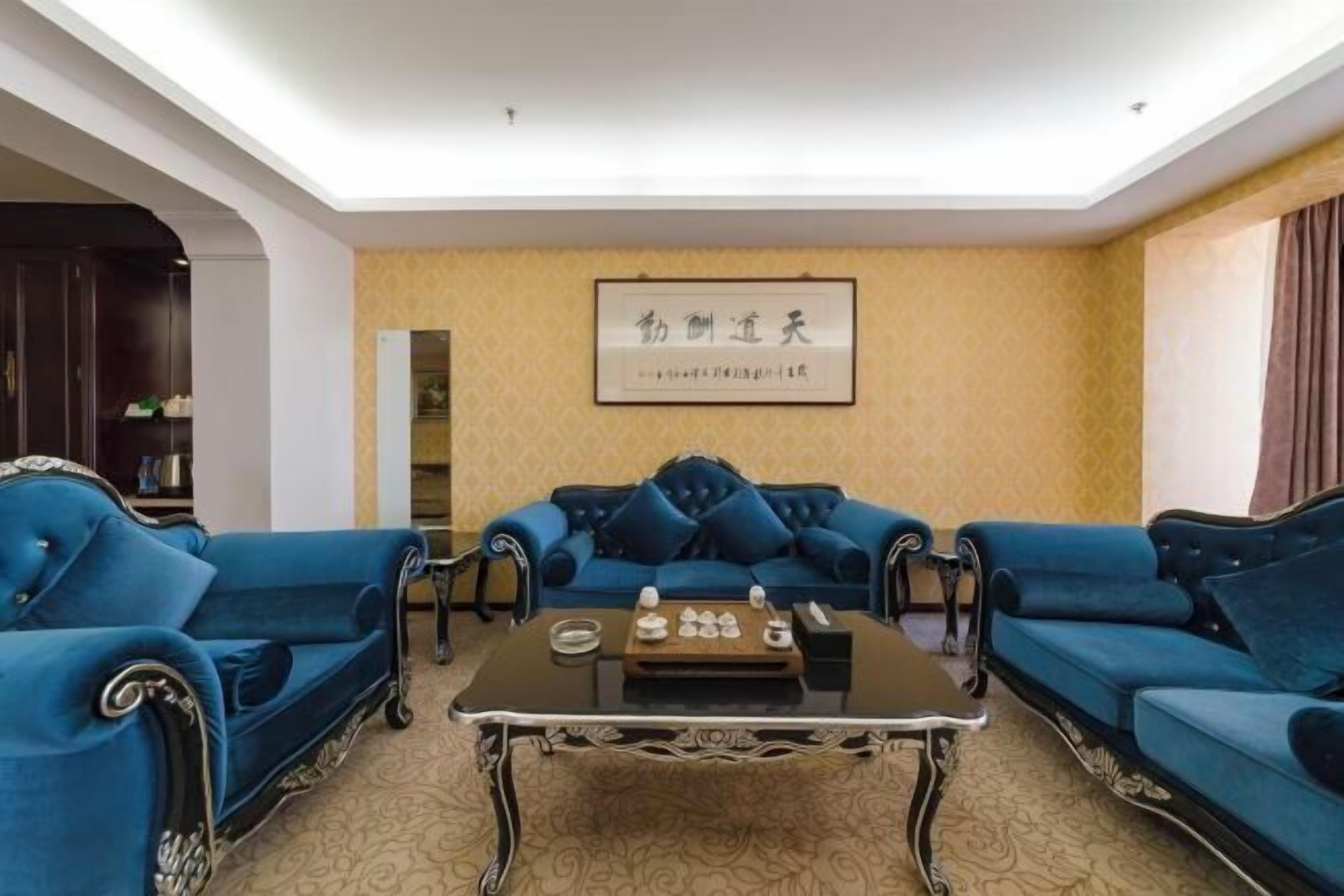 Un salón con un sofá azul, una mesa de centro negra y una obra enmarcada en la pared.