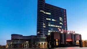 Un hôtel moderne à la façade incurvée, doté de plusieurs étages et d’une enseigne lumineuse.