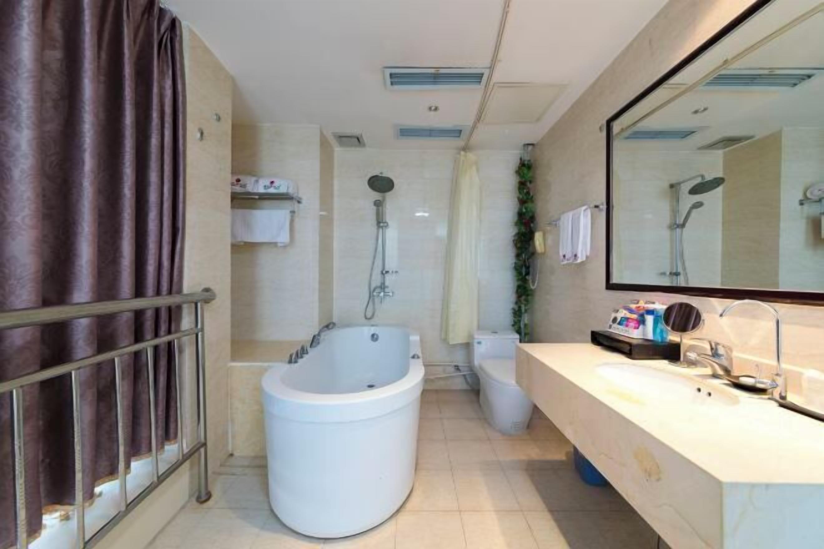 Une salle de bain moderne avec une baignoire, une douche, des toilettes et un grand miroir.