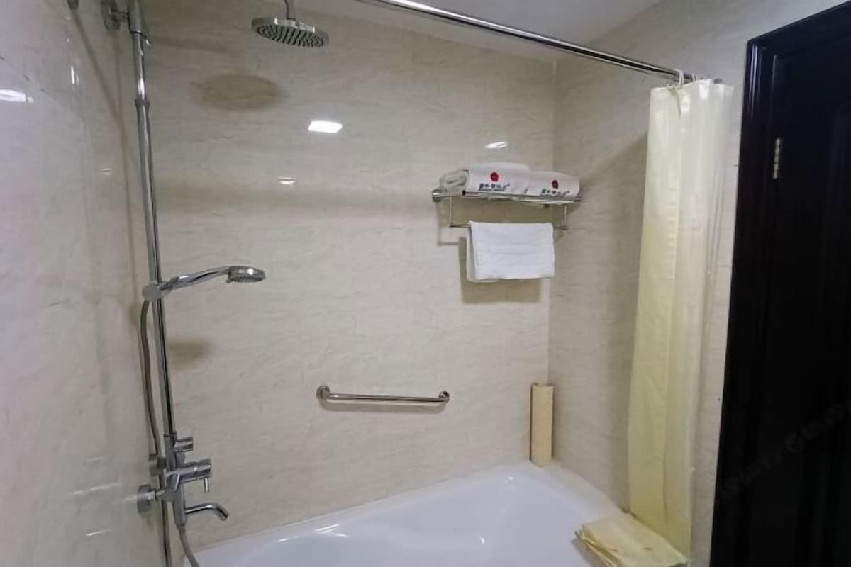 A bathroom with a shower, a bathtub, a towel rack, and a toilet paper holder.