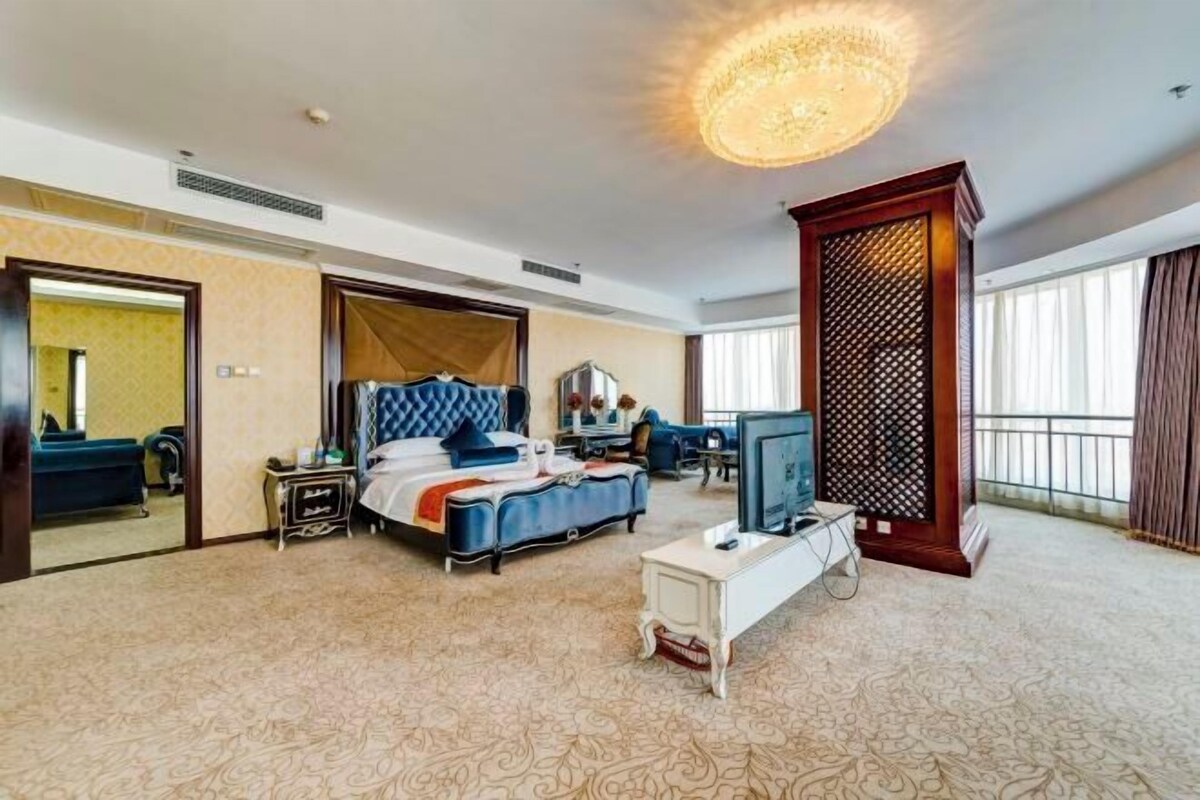 A hotel room with a bed, a desk, a television, and a large window.