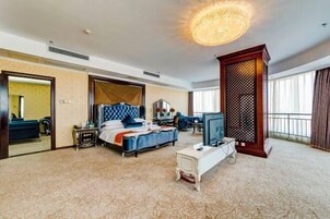 Una habitación de hotel con una cama, un escritorio, un televisor y un ventanal grande.