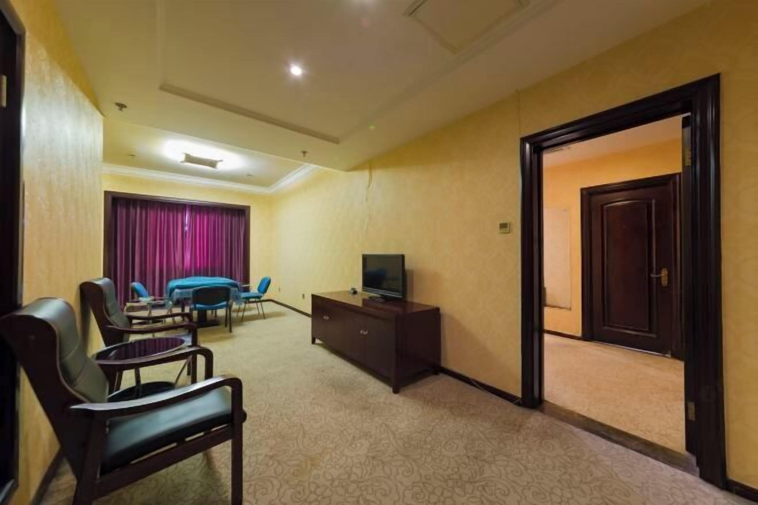Une chambre d’hôtel avec un grand lit, un téléviseur posé sur un meuble en bois, un bureau et une chaise.