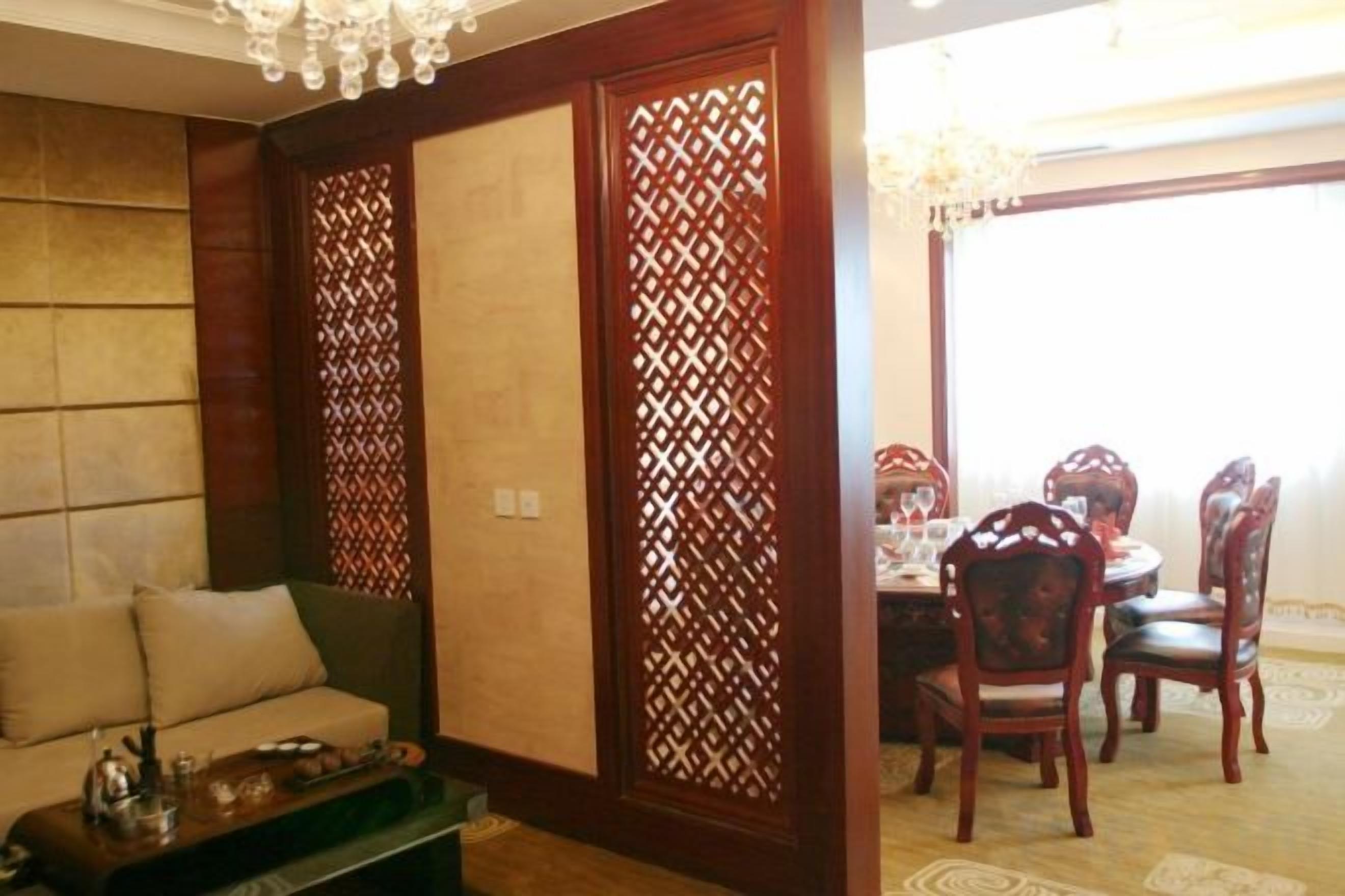 A room with a sofa, a dining table with chairs, and a decorative partition.