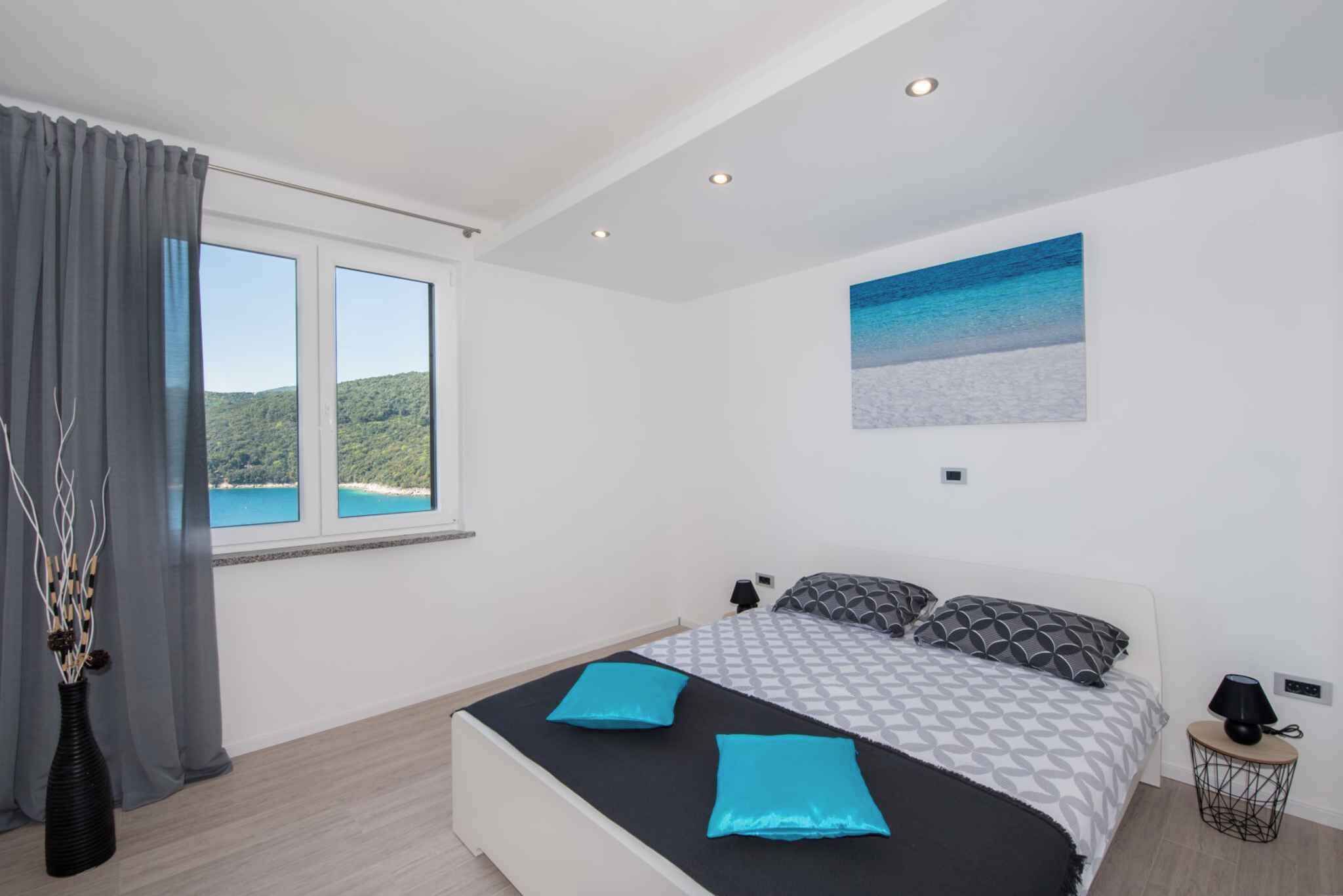 Ein Schlafzimmer mit einem großen Bett, einem Fenster mit Blick auf einen Wald und einem Gemälde an der Wand.