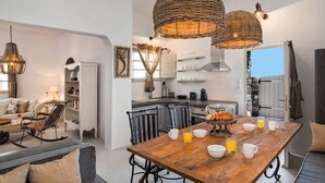 Una cocina moderna con una mesa de comedor de madera, sillas negras y lámparas colgantes de mimbre.