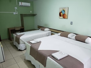 Ein Hotelzimmer mit zwei Betten, einem Sessel, einem kleinen Tisch und einer Klimaanlage an der Wand.