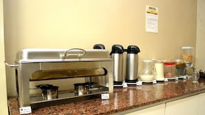 Ein Buffet mit Selbstbedienungsbereich, einschließlich Kaffeemaschine, Milchkännchen und verschiedenen Speisebehältern.