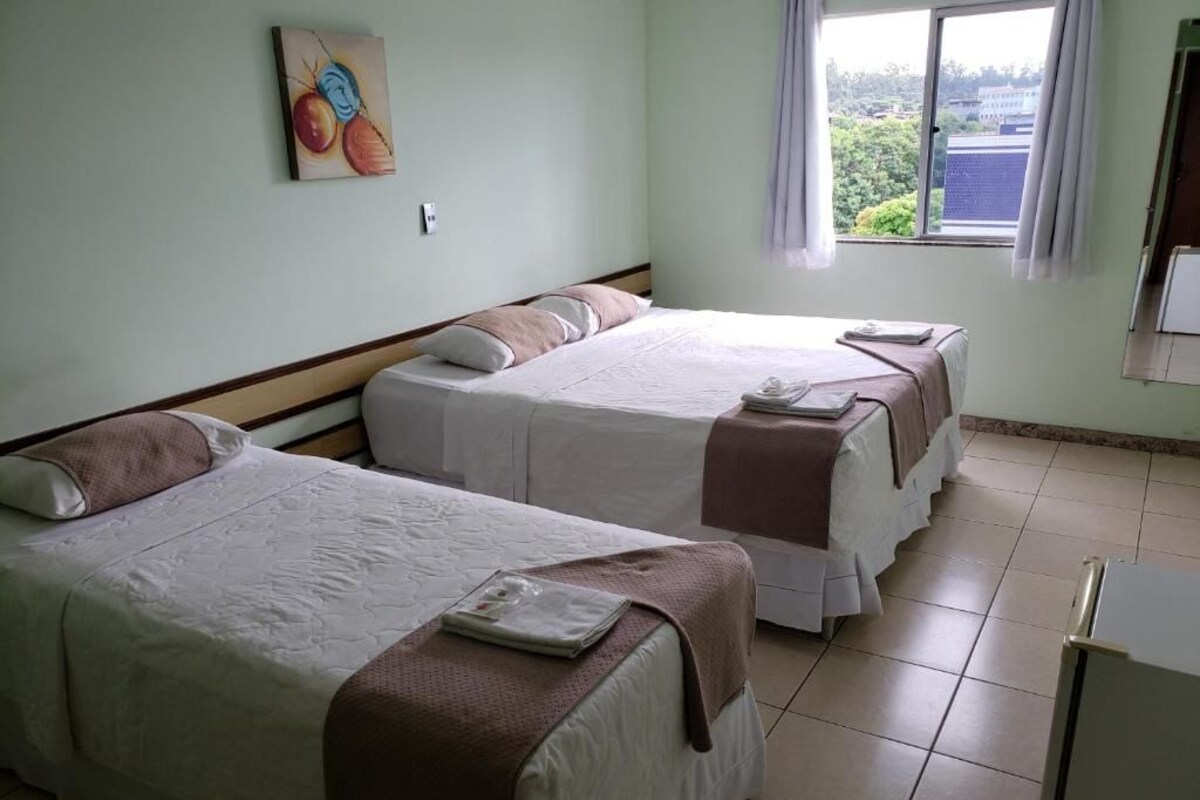 Et hotelværelse med to senge, et vindue med udsigt og et billede på væggen.