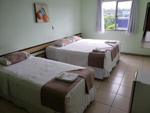 A hotel room with two beds, a window with a view, and a painting on the wall. - Domus Hotel Veneza (Ipatinga)