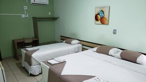Une chambre d’hôtel avec deux lits, une chaise, une petite table et un appareil de climatisation fixé au mur.