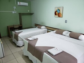 Une chambre d’hôtel avec deux lits, une chaise, une petite table et un appareil de climatisation fixé au mur.