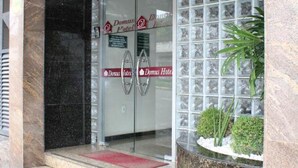 Ein Hotel Eingang mit Glastür, roher Fußmatte und Steinpflanzgefäß mit Pflanzen.