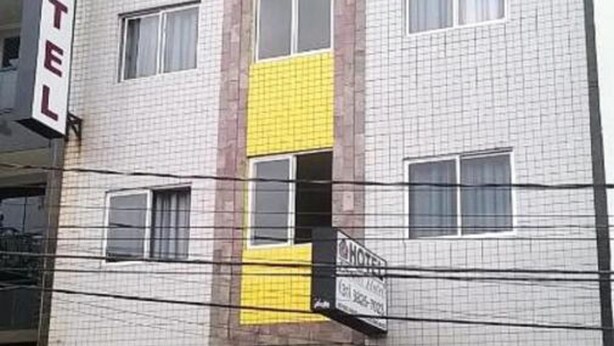 Un bâtiment d'hôtel avec de nombreuses fenêtres, une enseigne indiquant « DOMUS HOTEL », et une voiture garée devant.