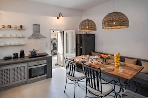 Eine moderne Küche mit Essbereich, ausgestattet mit einem Herd, einer Kaffeemaschine und einem Esstisch, gedeckt mit Tellern, Schüsseln und Früchten.