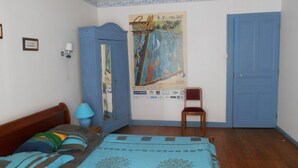 Ein Schlafzimmer mit einem Bett, einem Stuhl, einem Poster, einem Kleiderschrank und einer Tür.