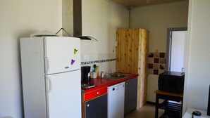 Eine kleine Küche mit einem weißen Kühlschrank, einer roten Arbeitsplatte, einem Spülbecken und einer Mikrowelle.