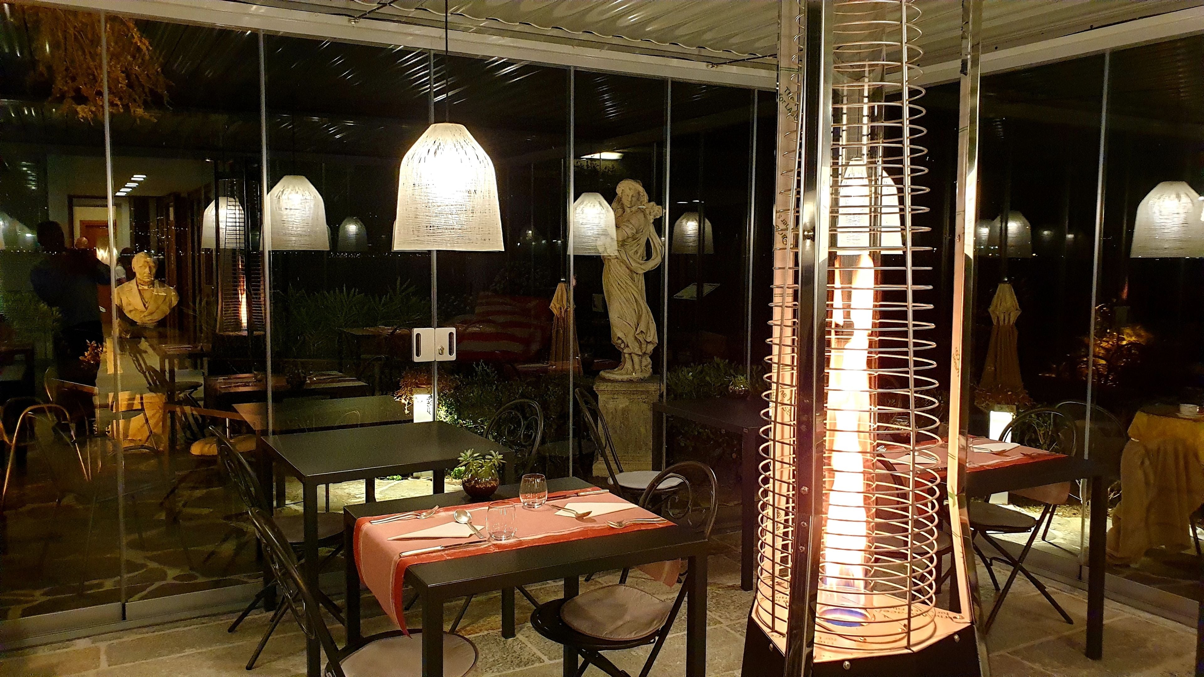 Un comedor interior con mesas y sillas, una estatua e iluminación decorativa.