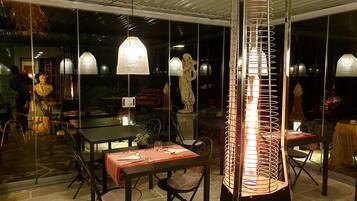 Un comedor interior con mesas y sillas, una estatua e iluminación decorativa.