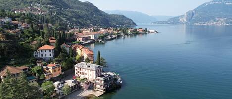 A coastal town with buildings along the waterfront, a clear view of the lake, and a mountainous backdrop.