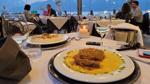 A dining table with plates of food, a candle, and a smartphone. - Meridiana Boutique Hotel (Bellano)