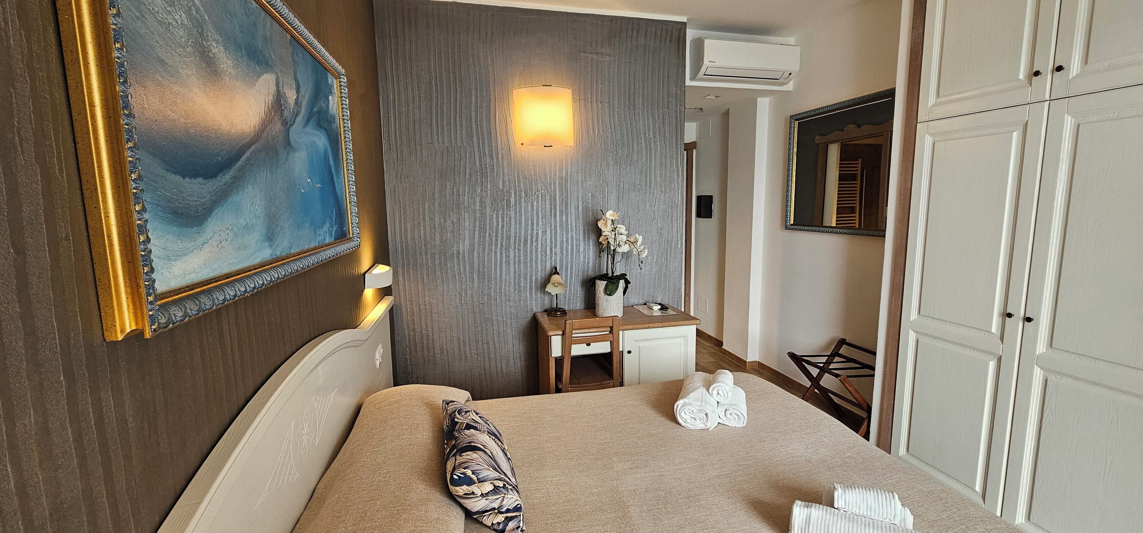 Une chambre d’hôtel équipée d’un lit, d’un bureau, d’un miroir et d’un climatiseur fixé au mur.