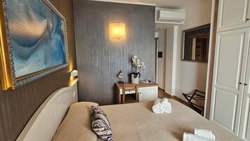 Une chambre d’hôtel équipée d’un lit, d’un bureau, d’un miroir et d’un climatiseur fixé au mur.