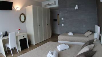 Une chambre d’hôtel avec deux lits, un bureau, une chaise, une armoire et un téléviseur fixé au mur.