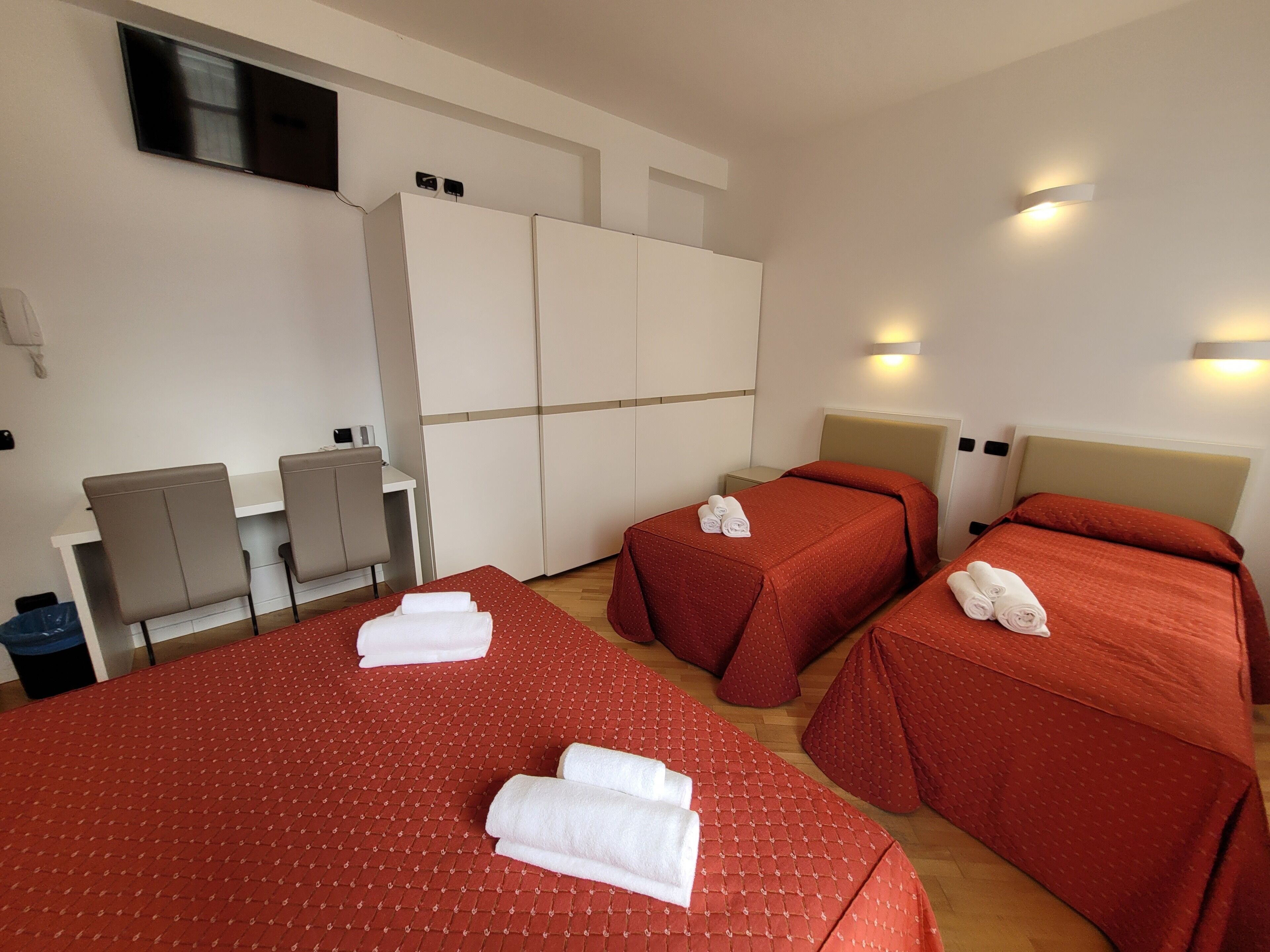 A hotel room with two beds, a desk, and a TV.