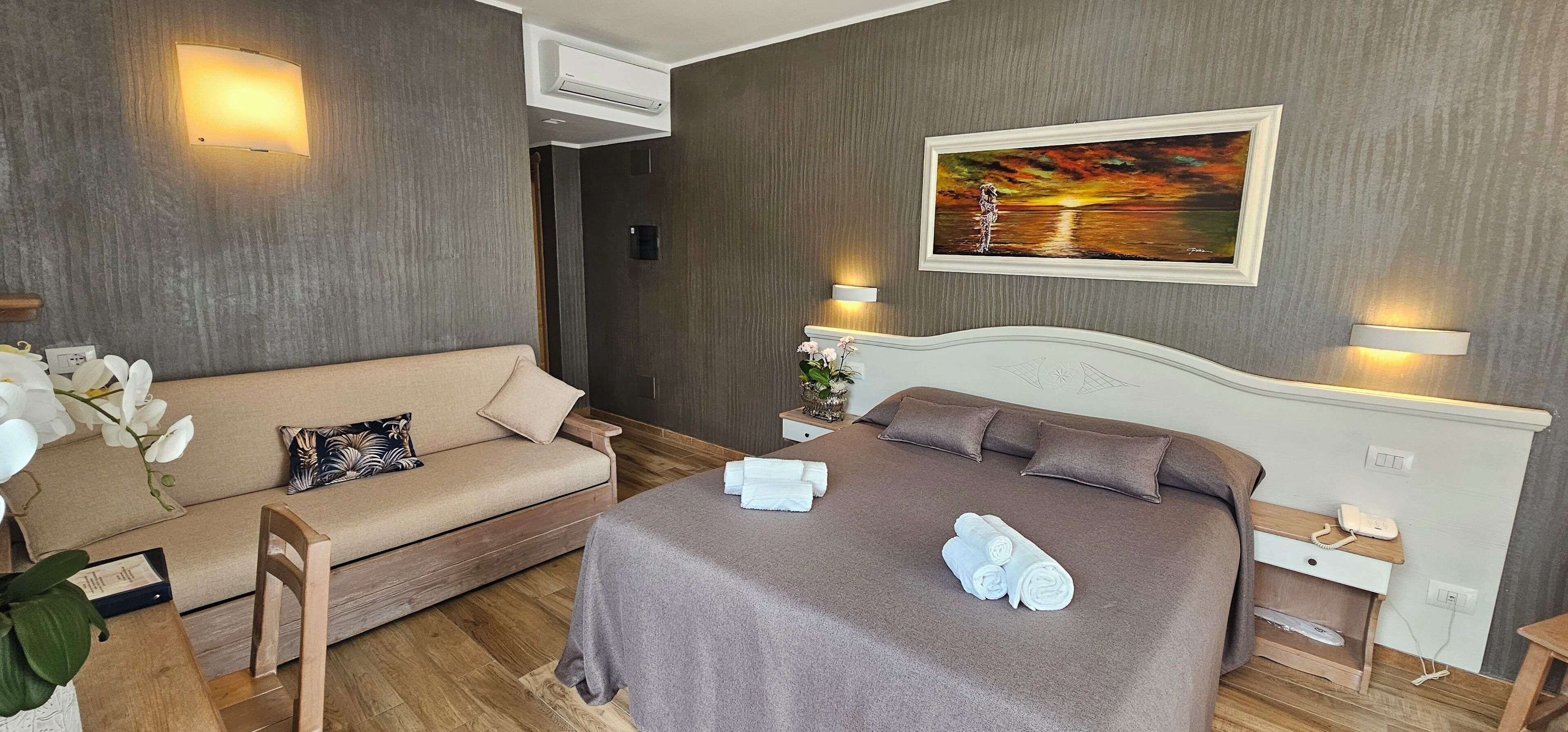 Una habitación de hotel con cama, sofá y un cuadro en la pared.