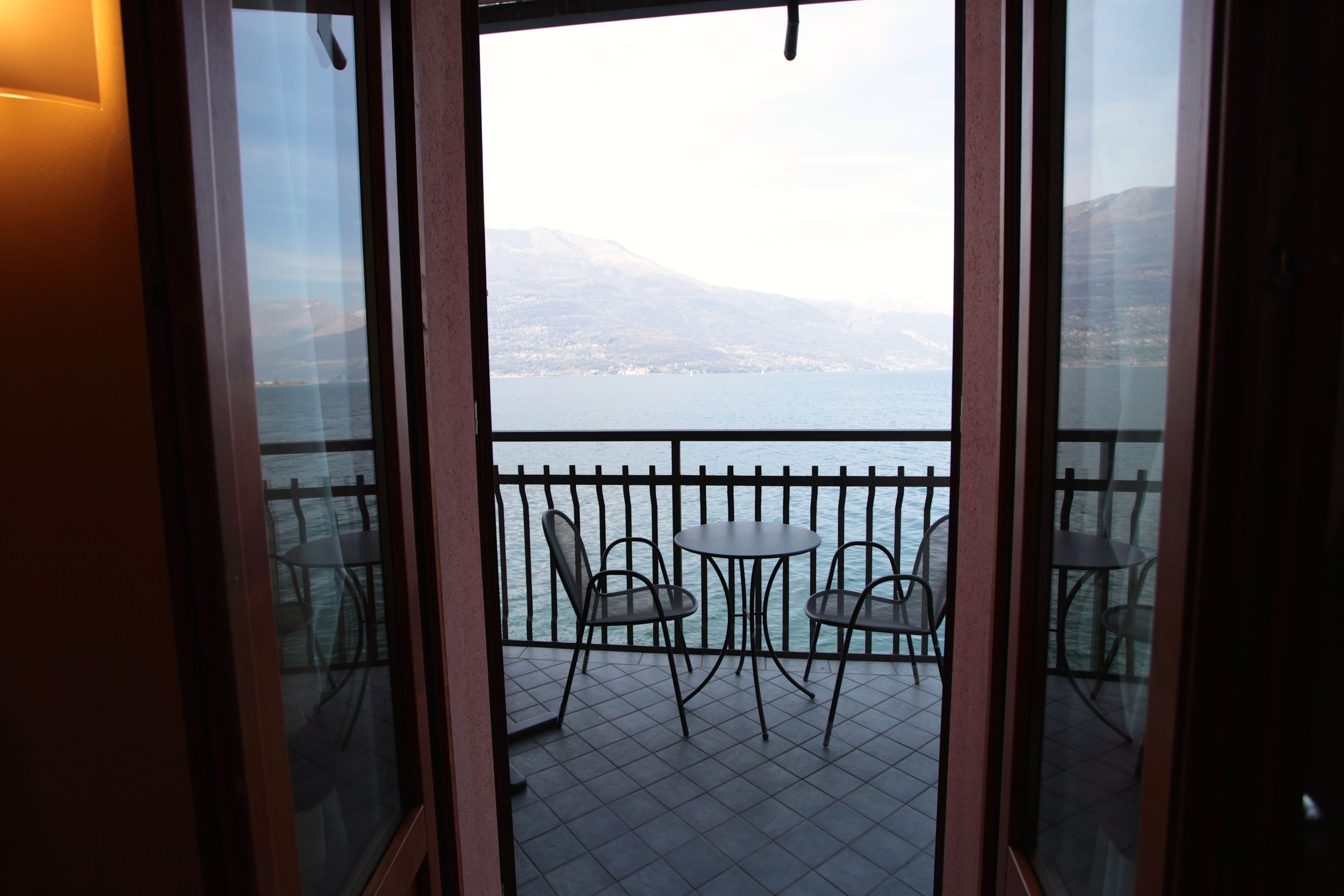 A balcony with a view of a body of water and distant mountains.