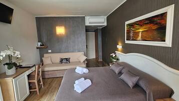 Hotelkamer met een bed, een bank, een bureau, een televisie en een schilderij aan de muur.