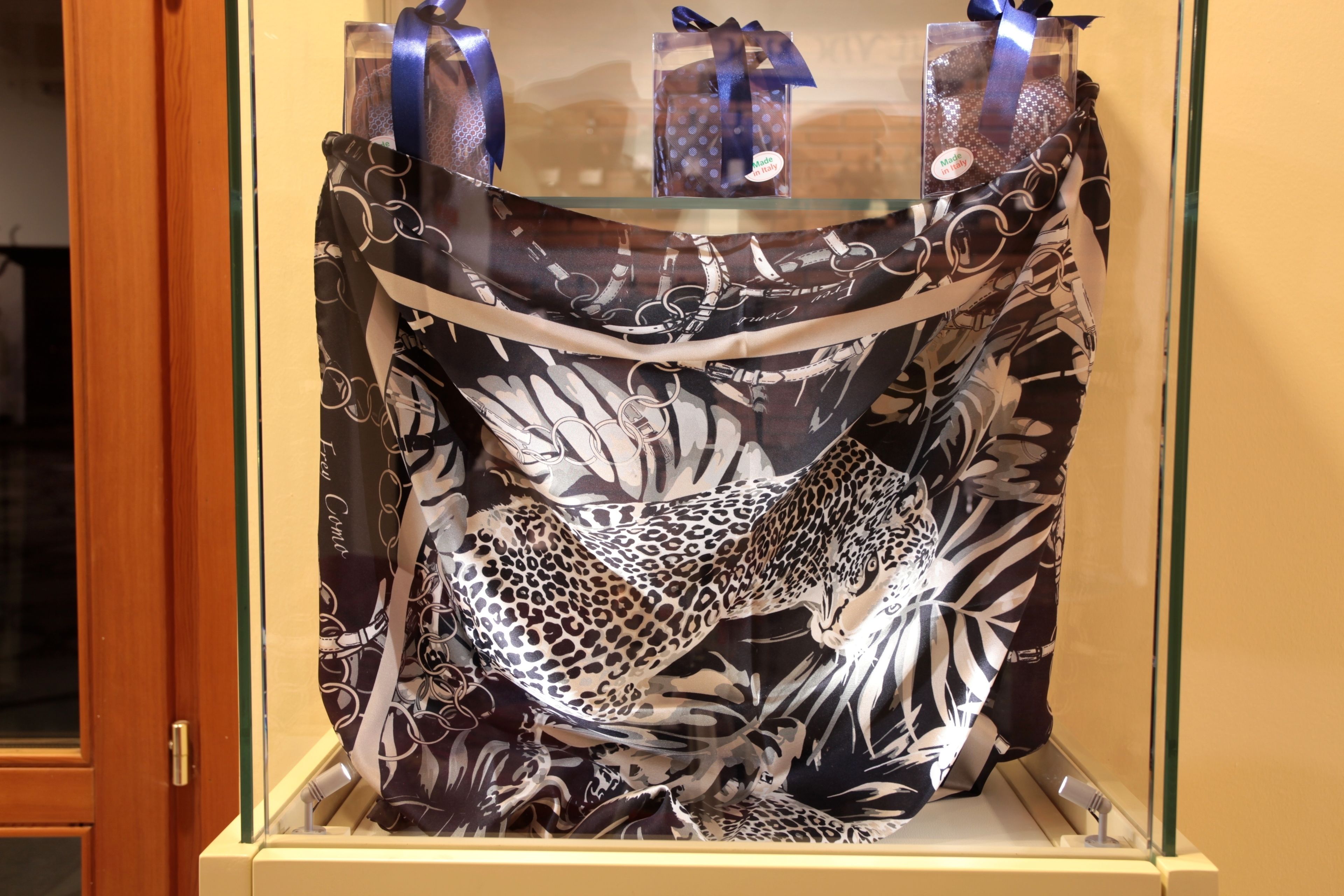 Tela de estampado de leopardo exhibida en una vitrina con tapa transparente, asegurada con cintas azules.