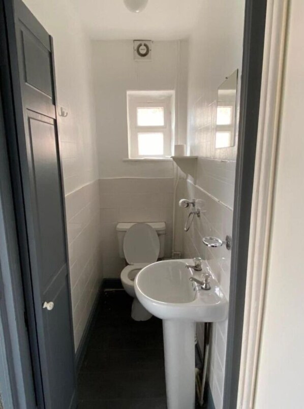 A compact bathroom with a toilet, sink, and a small window above the toilet.