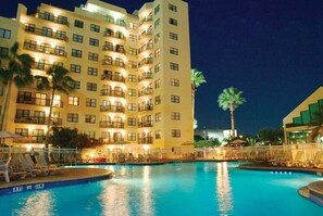 A multi-story hotel with a swimming pool, palm trees, and outdoor seating areas. - GREAT LOCATION RESORT STUDIO NEAR FL ATTRACTIONS❤ (Orlando)