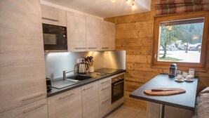 Eine moderne Küche mit Holzschränken, Edelstahlgeräten und einem Fenster mit Blick ins Freie.