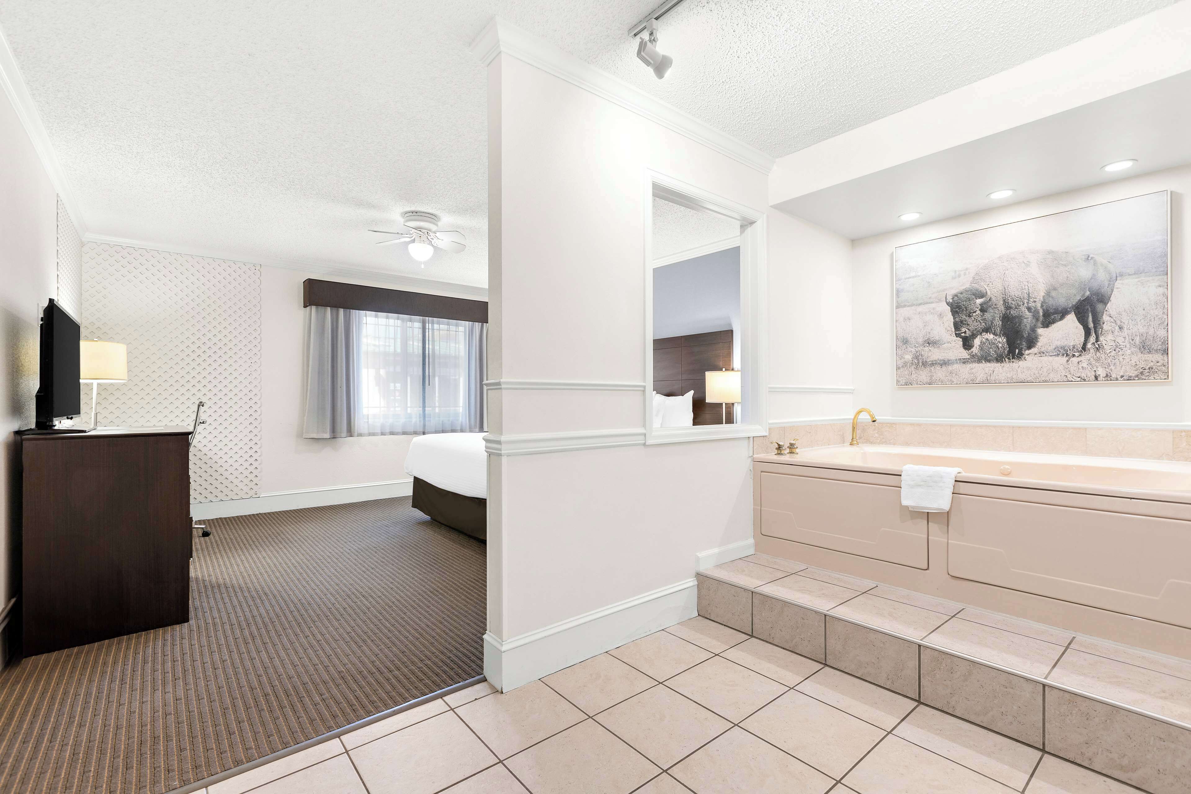 Une chambre d’hôtel comprenant un lit, un bureau, une salle de bain avec baignoire et un grand miroir.