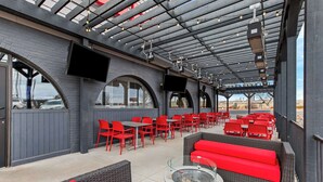 An outdoor patio with red seating, a fire pit, and a covered area with a TV screen. - Best Western Downtown Casper Hotel (Casper)