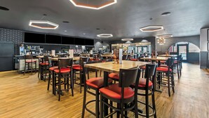 A modern restaurant with hexagonal ceiling lights, wooden tables, and red cushioned chairs. - Best Western Downtown Casper Hotel (Casper)