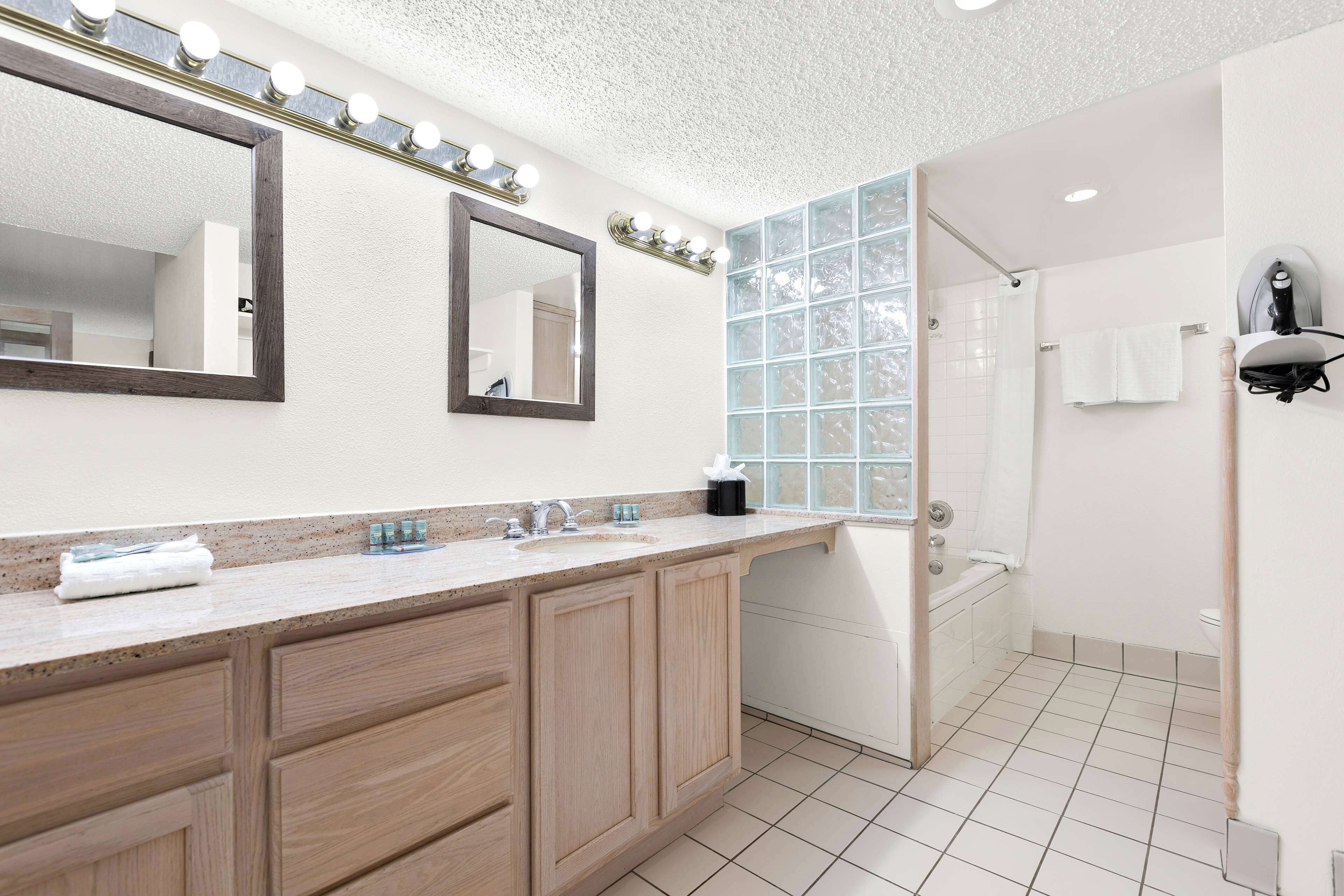 A modern bathroom with a vanity, a large mirror, and a shower area.