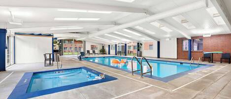 Una amplia piscina cubierta con carriles delimitados, un trampolín y una silla para socorrista.