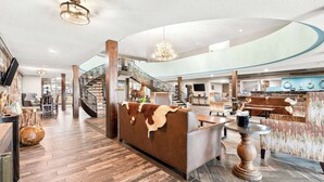A spacious lobby with a central reception desk, a staircase, and a seating area with a leather couch. - Best Western Downtown Casper Hotel (Casper)