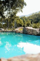 Una piscina azul clara rodeada de rocas y vegetación.