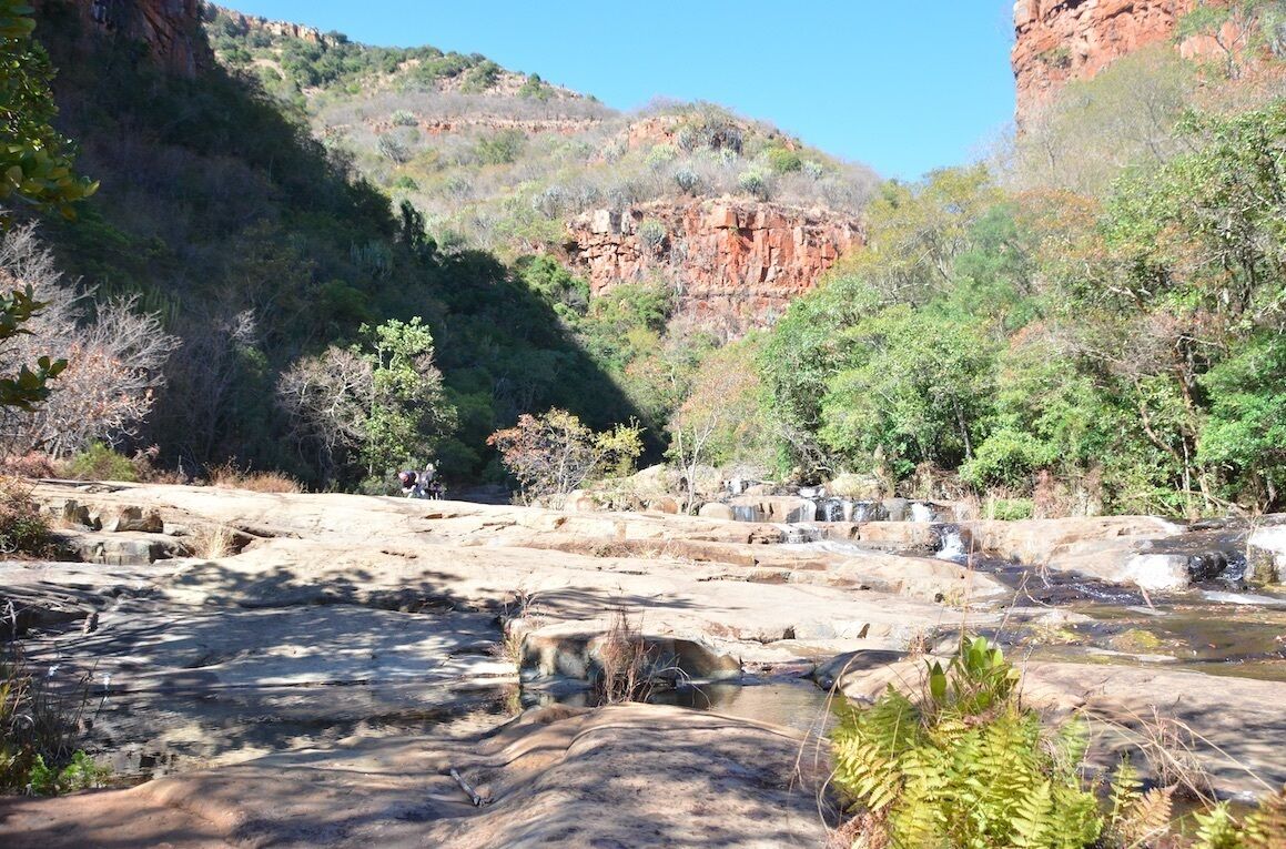 A natural landscape with a rocky riverbed and surrounding vegetation.