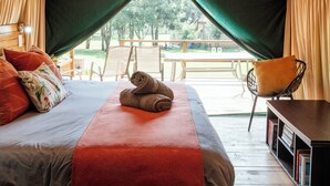 A tented accommodation with a bed, pillows, a rolled towel, a chair, and a table. - Rocky Drift Private Nature Reserve (Emgwenya)