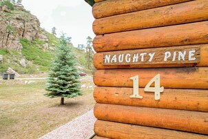 Una baita di legno con un cartello che riporta la scritta 'NAUGHTY PINE 14'.